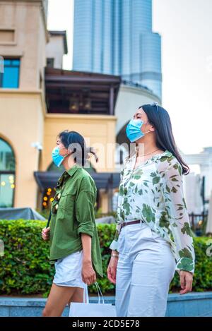 Deux amies asiatiques femme portant un masque chirurgical à l'extérieur du centre commercial de Dubaï. Voyage et loisirs nouveau normal après coronavirus COV Banque D'Images