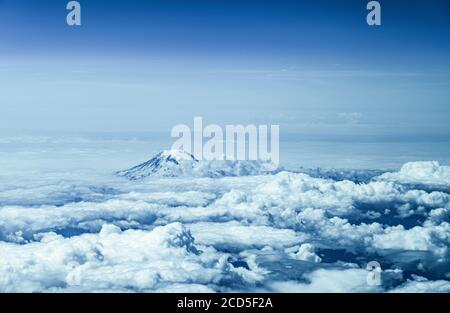 Aerial view of mountain peak rising above clouds Stock Photo