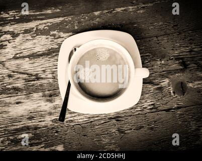 Vue en noir et blanc d'une tasse de café fraîche une table abîmé par le dessus Banque D'Images