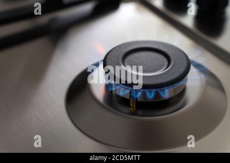 Gros plan sur une flamme bleue provenant d'un brûleur à gaz. Surface de cuisine en acier inoxydable. Banque D'Images
