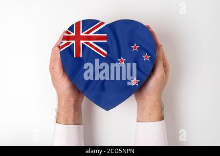 Drapeau de la Nouvelle-Zélande sur une boîte en forme de coeur dans les mains d'un homme. Arrière-plan blanc Banque D'Images
