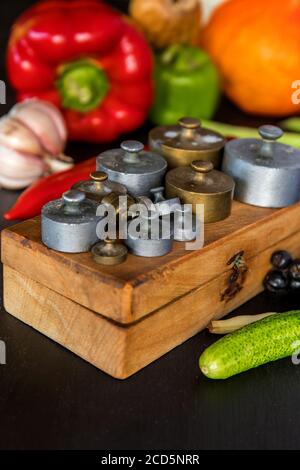 Anciens poids en laiton. Poids sur les anciennes balances. Légumes frais et vieux pèse-personne sur fond noir. Banque D'Images