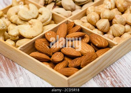 Gros plan d'amandes dans une boîte en bois. Assortiment de noix en arrière-plan. Banque D'Images