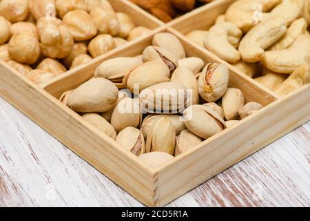 Gros plan de pistaches dans une boîte en bois. Assortiment de noix en arrière-plan. Banque D'Images