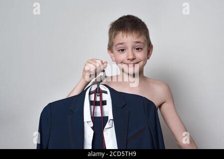 Garçon tient dans ses mains costume d'affaires uniforme d'école. Joyeux garçon qui va à l'école Banque D'Images
