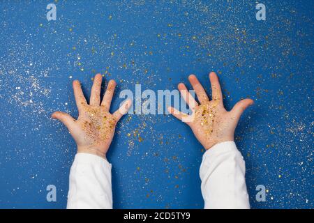 Les mains des enfants tiennent des étoiles dorées sur fond bleu étincelant. Banque D'Images