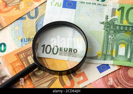 Loupe sur billet de 100 euros. Vérifiez l'authenticité de l'argent. Concept de richesse, d'épargne en espèces, de comptabilité des revenus et des dépenses. Vue de dessus. Banque D'Images