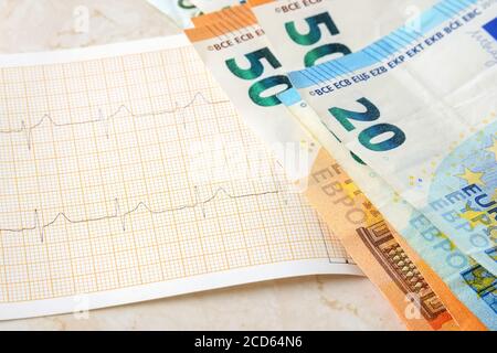 Euro papier argent sur cardiogramme gros plan. Économies en espèces pour le traitement et les soins de santé, comptabilité des revenus et des dépenses concept. Vue avant. Banque D'Images