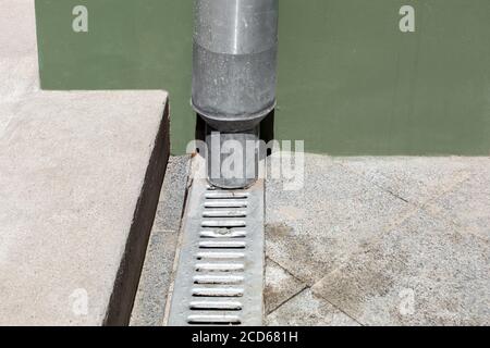 structure d'ingénierie tuyau de descente sur bâtiment de façade verte avec grille de drainage de sol en pierre grise et avec seuil de ciment, détails de clôture ur Banque D'Images