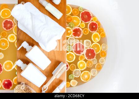 Baignoire avec un mélange de tranches d'agrumes frais et un ensemble spa de produits naturels. Banque D'Images