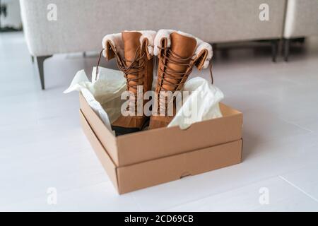 Nouvelles bottes d'hiver acheter de nouvelles chaussures de randonnée en ligne shopping et livraison. Ouverture de la boîte à chaussures dans le salon à la maison Banque D'Images