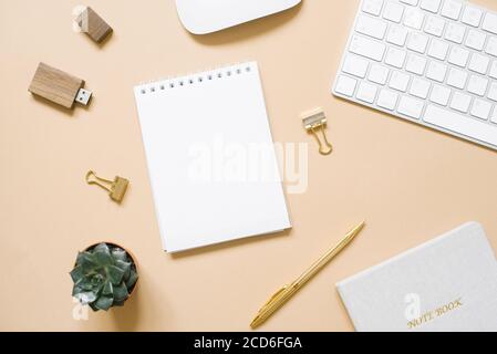 Papeterie de bureau sur fond beige. Stylet, Bloc-notes, trombone, clé usb, ordinateur. Vue de dessus de l'espace de travail Banque D'Images