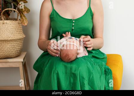 Maman et nouveau-né à la maison. La vie à la maison avec un animal de compagnie. Couleur de robe verte. Banque D'Images