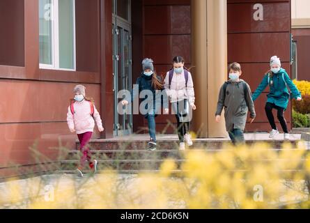 Les enfants des élèves qui se trouvent dans un masque médical quittent l'école. Banque D'Images