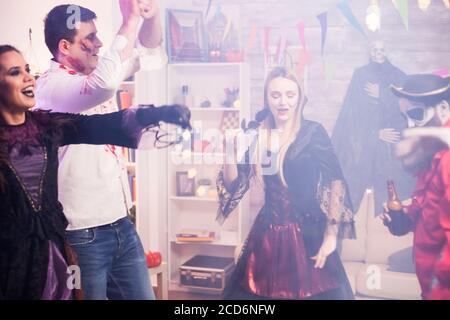 Groupe de personnes célébrant halloween dans une salle avec fumée. Des costumes effrayants. Banque D'Images