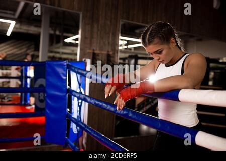 caleçons musclés fatiguées après un entraînement intense et efficace en salle de gym, portant des vêtements de sport, des bandages protecteurs rouges Banque D'Images