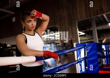 caleçon de femme caucasienne fatiguée debout se pencher sur la clôture, après l'entraînement réussi dans l'anneau. Concept sport Banque D'Images