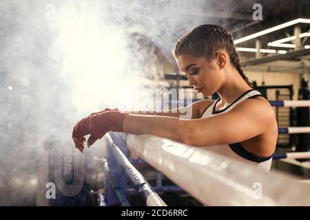 caleçon de femme caucasienne fatiguée debout se pencher sur la clôture, après l'entraînement réussi dans l'anneau. Concept sport Banque D'Images