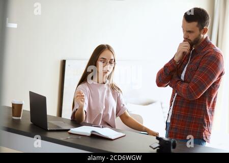 Portrait d'un jeune couple discutant de questions familiales, regardant l'écran, prenant des notes, exprimant la curiosité, à la maison, portrait Banque D'Images