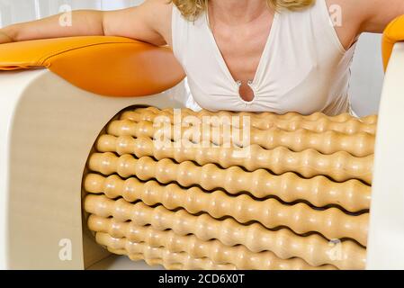 femme souriante faisant un massage pour l'estomac. La machine de massage en rouleau est un moyen de façonner la figure. Soins de la peau, concept. Équipement de massage relaxant moderne. Banque D'Images