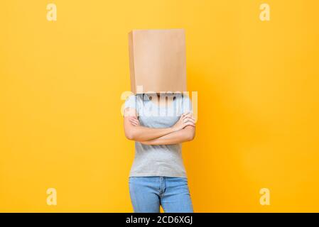 Portrait de concept de la femme anonyme avec la tête couverte de papier sac faisant des bras mouvement croisé sur fond jaune studio Banque D'Images