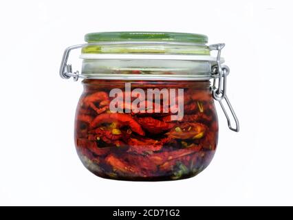 Tomates séchées dans un pot avec de l'huile d'olive et des herbes isolé sur un fond blanc Banque D'Images