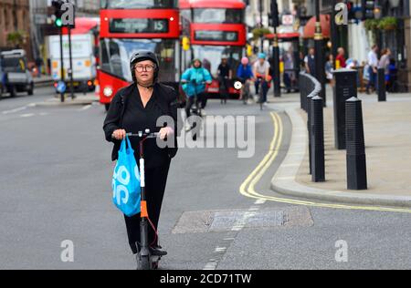 Londres, Angleterre, Royaume-Uni. Femme avec shopping sur un scooter électrique à Whitehall Banque D'Images