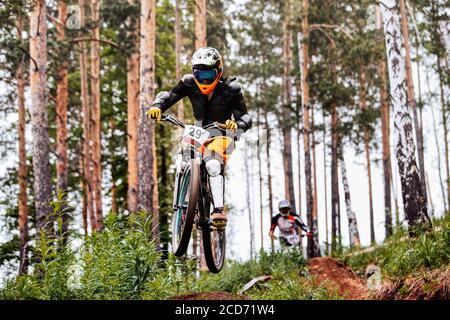 les athlètes en vélo de descente font une course sur piste dans la forêt de pins Banque D'Images