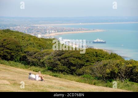 Deux personnes assises sur l'herbe en regardant vers Eastbourne, au loin de Beachy Head, East Sussex, Angleterre Banque D'Images