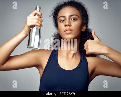 Femme sportive tenant en main une bouteille avec de l'eau saine geste de main positif alimentaire Banque D'Images