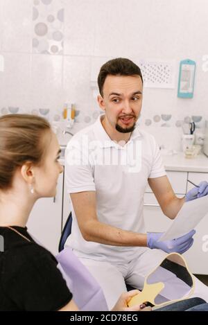 Le dentiste montre une radiographie des dents du patient à une femme mignonne. Réception chez le dentiste. Banque D'Images