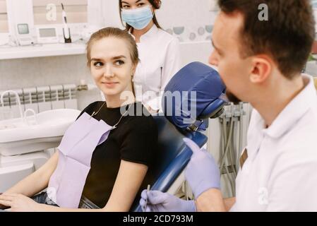 Dentiste parlant à un patient. L'assistant dentaire se trouve à proximité. Réception au bureau des dentistes et traitement dentaire. Banque D'Images