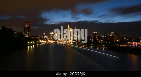 26 août 2020, Hessen, Francfort-sur-le-main : tandis que les nuages sont chassés par des rafales de vent au-dessus de l'horizon illuminé de la ville bancaire, un navire de fête laisse ses traces sur le main. (Prise de vue avec une vitesse d'obturation plus élevée) photo : Arne Dedert/dpa Banque D'Images