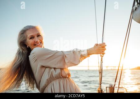 Belle femme âgée debout sur un yacht et regardant appareil photo Banque D'Images