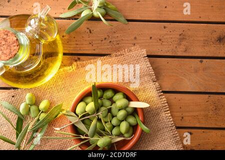 Branches d'olive remplies d'olives sur une table en bois avec un récipient à huile et un récipient à argile. Concept de récolte d'olives pour la fabrication d'olives. Vue de dessus Banque D'Images