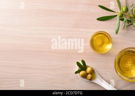 Huile d'olive végétale dans des bols en verre sur le banc de cuisine avec cuillère et branche d'olive. Vue de dessus. Banque D'Images