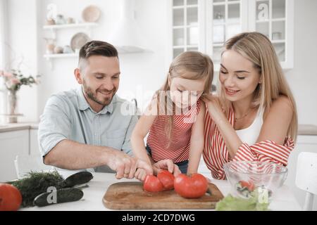 Une petite fille mignonne et ses beaux parents cuisent cuisine à la maison Banque D'Images