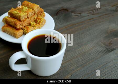 Tasse de café turc sur table en bois avec pistache floue Pâtisseries aux noix de Baklava en toile de fond Banque D'Images