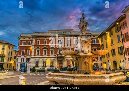 Brescia, Italie, 10 septembre 2019: Fontaine, restaurant de rue et Credito Agrario Bresciano bâtiment de banque sur la place Piazza Paolo VI dans le centre historique, vue du crépuscule en soirée, Lombardie Banque D'Images