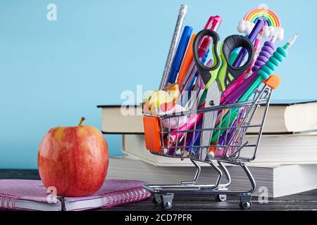 Bannière du panier avec fournitures scolaires sur fond bleu avec une pile de livres et une pomme avec un espace de copie. Concept de retour à l'école Banque D'Images