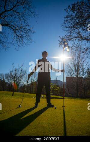 Golfeur sur le putting Green et tenant le drapeau de golf et Putter de golf avec la lumière du soleil. Banque D'Images