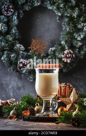 Cocktail Eggnog nouvel an ou Noël - boisson chaude d'hiver ou d'automne avec lait, œufs et rhum foncé, saupoudrée de cannelle et de muscade dans un verre sur bois Banque D'Images