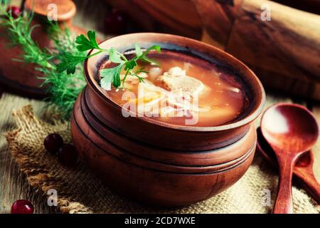 Soupe russe traditionnelle de choucroute, viande et pommes de terre dans un pot d'argile, fond de bois vintage, style rustique, concentration sélective Banque D'Images