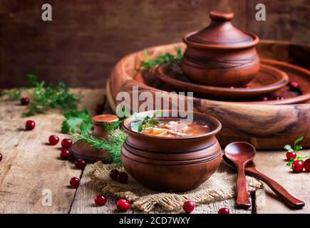 Soupe russe traditionnelle de choucroute, viande et pommes de terre dans un pot d'argile, fond de bois vintage, style rustique, concentration sélective Banque D'Images