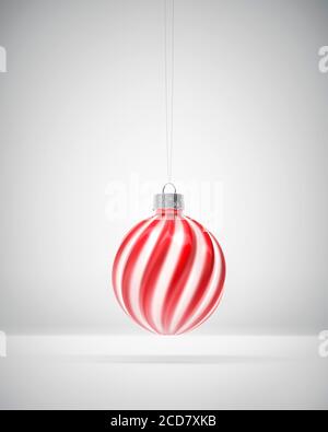 Boule de Noël à rayures tordues rouges et blanches. Arrière-plan ombré blanc. Décoration de Noël, concept d'atmosphère festive. Banque D'Images
