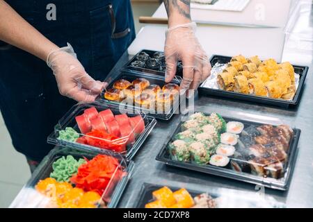 Livraison de sushis. De nombreuses variétés de sushi dans une boîte en plastique sont préparées pour la livraison. Banque D'Images