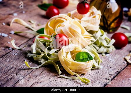 Encore une vie dans un style rustique. Nid de pâtes avec tomates cerises, huile d'olive et basilic vert. Arrière-plan en bois vintage, mise au point sélective, faible profondeur o Banque D'Images
