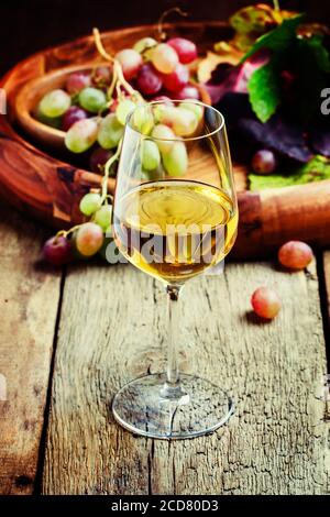 Vin blanc dans un verre de raisin d'automne, vieux fond en bois, foyer sélectif Banque D'Images