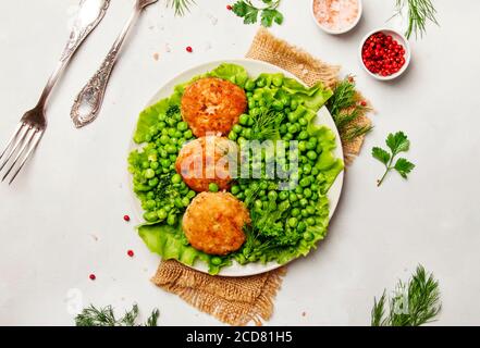 Côtelettes de poisson de morue avec garniture de pois verts et de brocoli, fond blanc, vue de dessus Banque D'Images