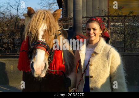Alba Iulia, Roumanie - 01.12.2018: Belle jeune femme vêtue de vêtements traditionnels debout à côté de son cheval Banque D'Images